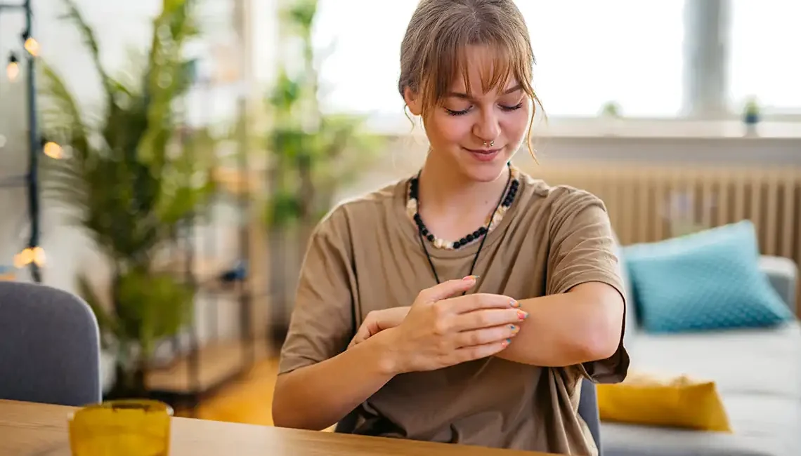 sentimos picor. Chica rascándose el brazo