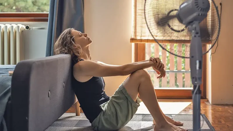 Golpe de calor. Mujer en casa con ventilador
