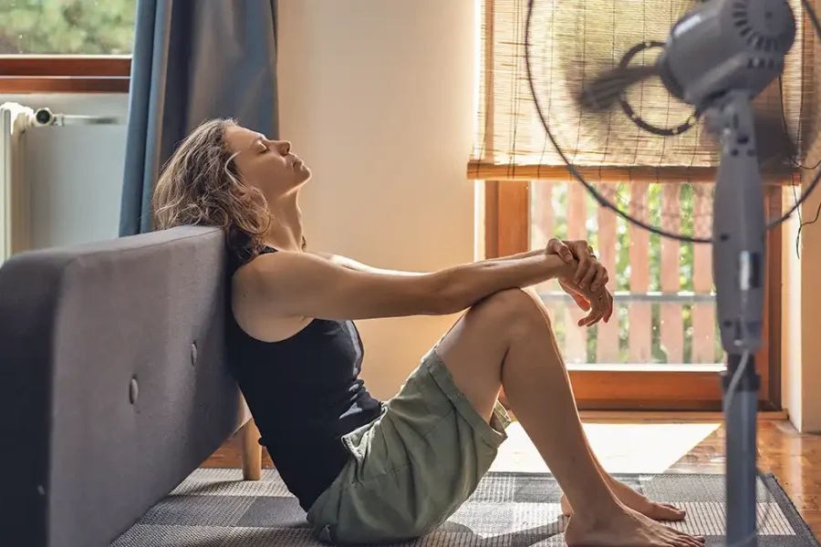 Golpe de calor. Mujer en casa con ventilador