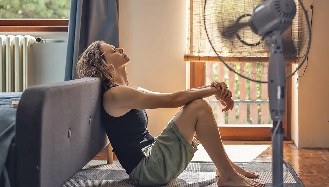 Golpe de calor. Mujer en casa con ventilador