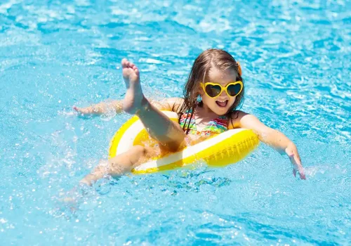 Protección solar niños. Menor con flotador en piscina