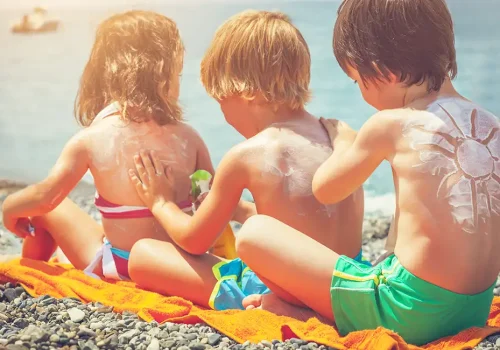 Protección solar niños. Niños aplicandose crema solar
