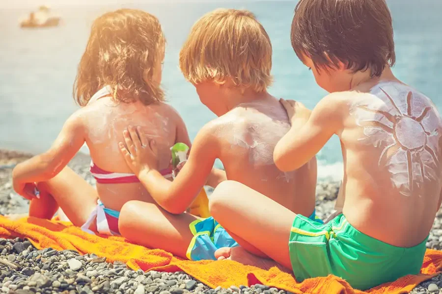 Protección solar niños. Niños aplicandose crema solar