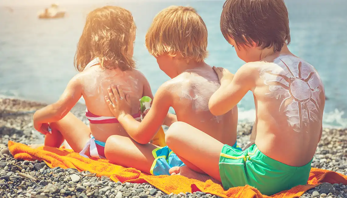 Protección solar niños. Niños aplicandose crema solar